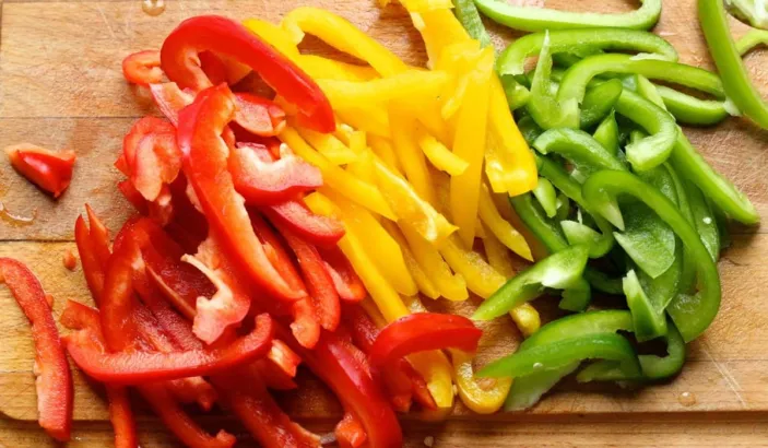 Red, yellow and green bell peppers cut into pieces.