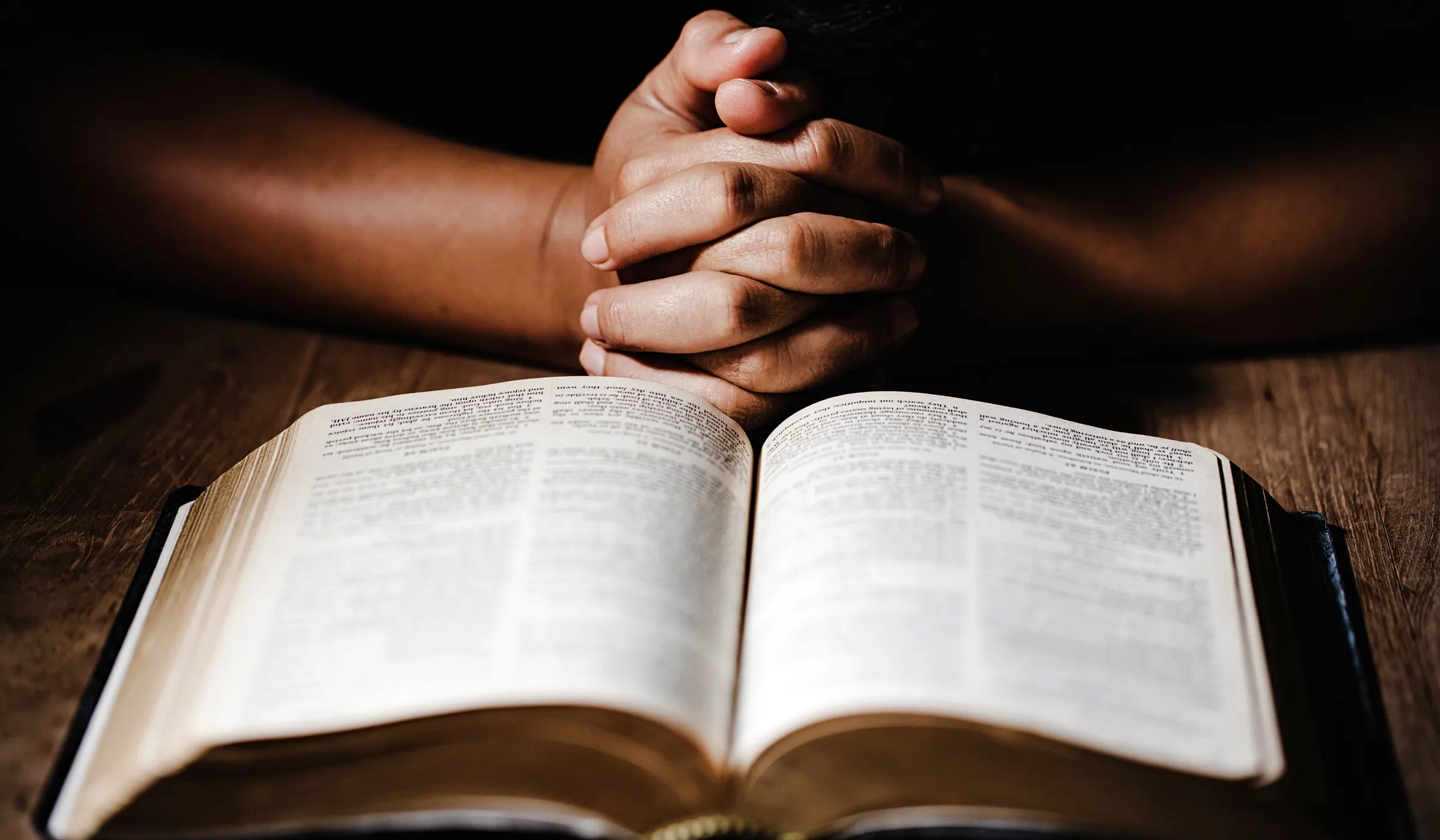Hands with fingers crossed over a bible